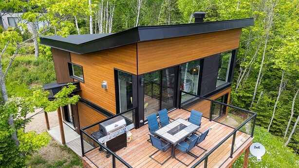 Une cabane moderne dotée d’une terrasse, d’un barbecue extérieur et d’un espace repas.