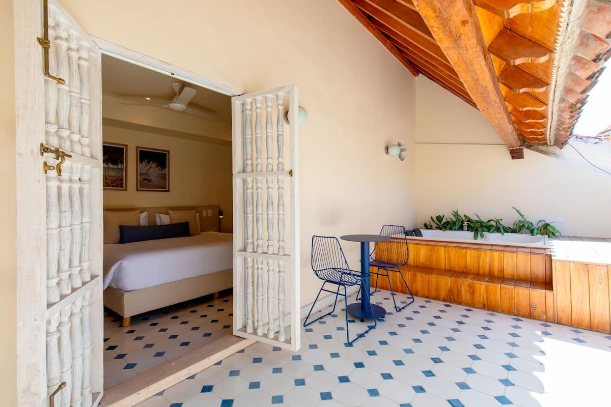 Una habitación con cama, una pequeña mesa con sillas, zona de bar y vistas al exterior.