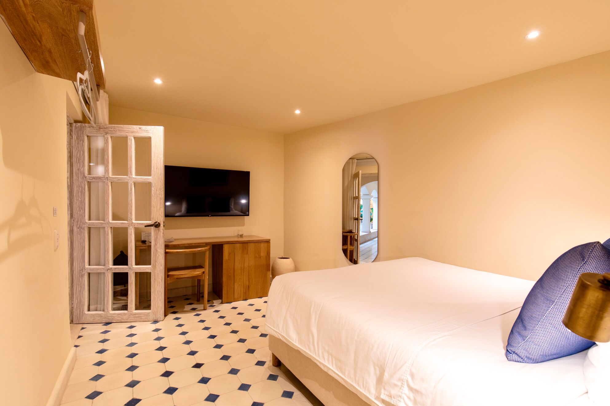 Une chambre à coucher avec un lit, un bureau, une télévision et un miroir.