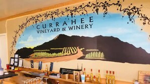 Un espace bar agrémenté d’une fresque représentant un vignoble et d’une enseigne indiquant : « CURRAHEE VINEYARD & WINERY ».