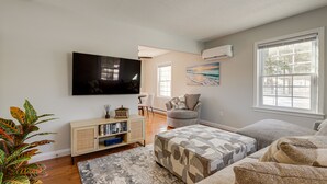 A living room with a sofa, a TV, a bookshelf, and a window. - Niantic Duplex w/ Deck < 1 Mi to Beach + Boardwalk (Niantic)