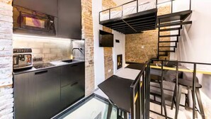 A compact kitchen with modern appliances, a built-in oven, and a brick accent wall. - Cuddle Puddle  (Vilnius)