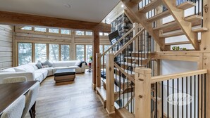 A spacious living area with a wooden staircase and a white sofa. - New 5 bed 4 bath cottage on Turtle Lake, Privacy! (Seguin)