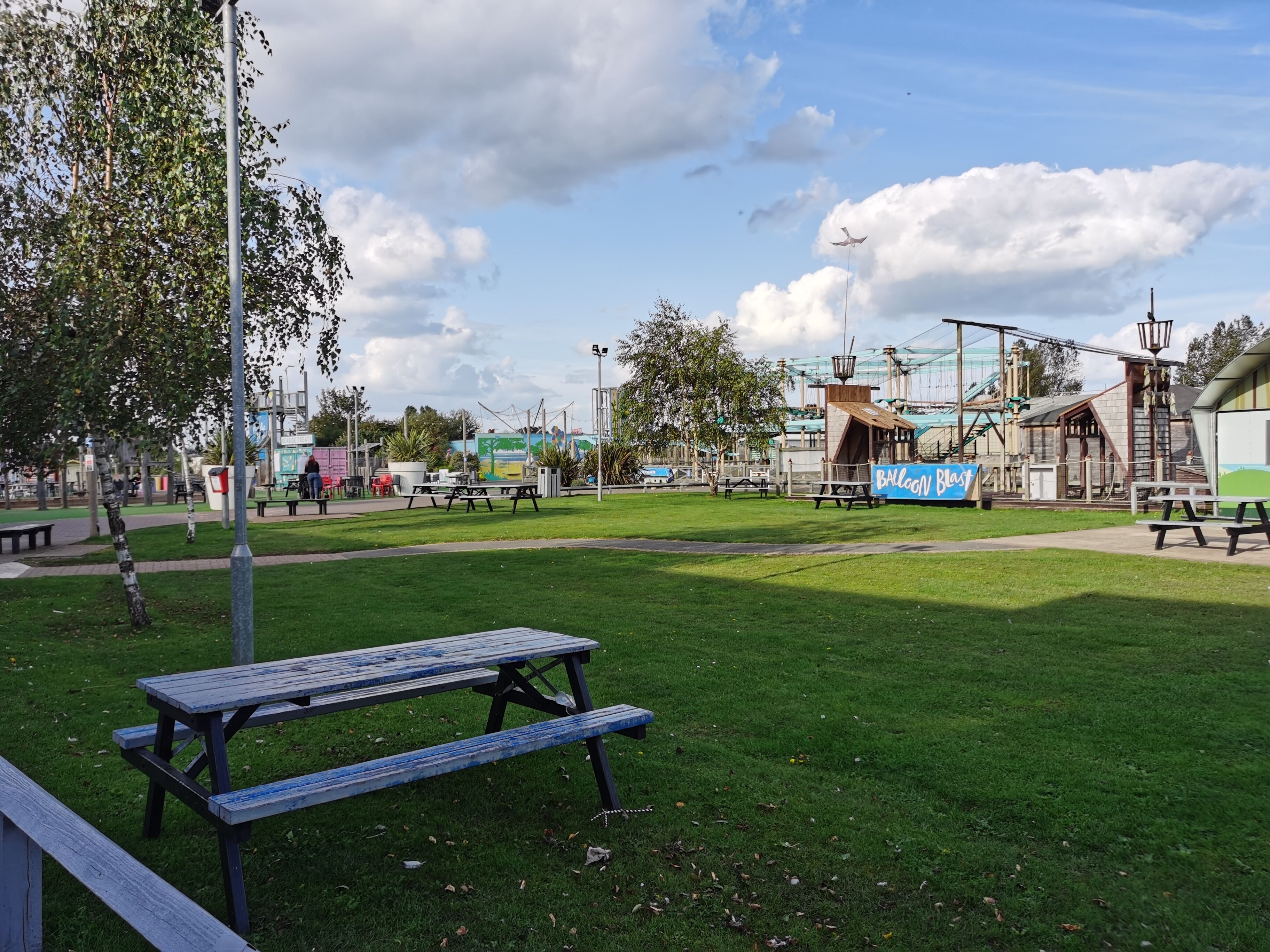 A park with picnic tables, a playground, and a balloon blast attraction.