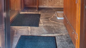 Un interno in legno con una panca, pavimento in pietra e una finestra.