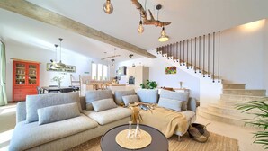 Ein modernes Wohnzimmer mit einer Eckcouch, einem runden Couchtisch und einer Treppe mit Geländer.