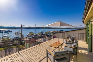 A deck with outdoor seating, a view of boats on water, and a clear sky.