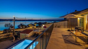 Ein Balkon mit Pool, Sitzgelegenheit im Freien und Blick auf Wasser und Boote.
