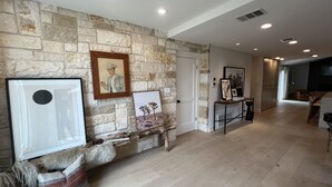 A spacious living area with a stone wall, a fireplace, and a seating area with a fur throw and pillows.
