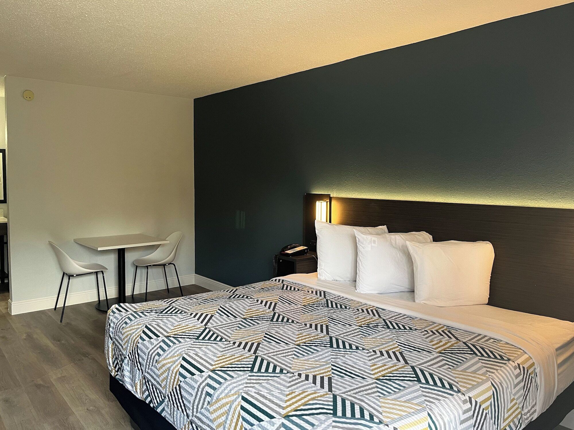 Una habitación de hotel moderna con una cama grande, un escritorio y dos sillas.