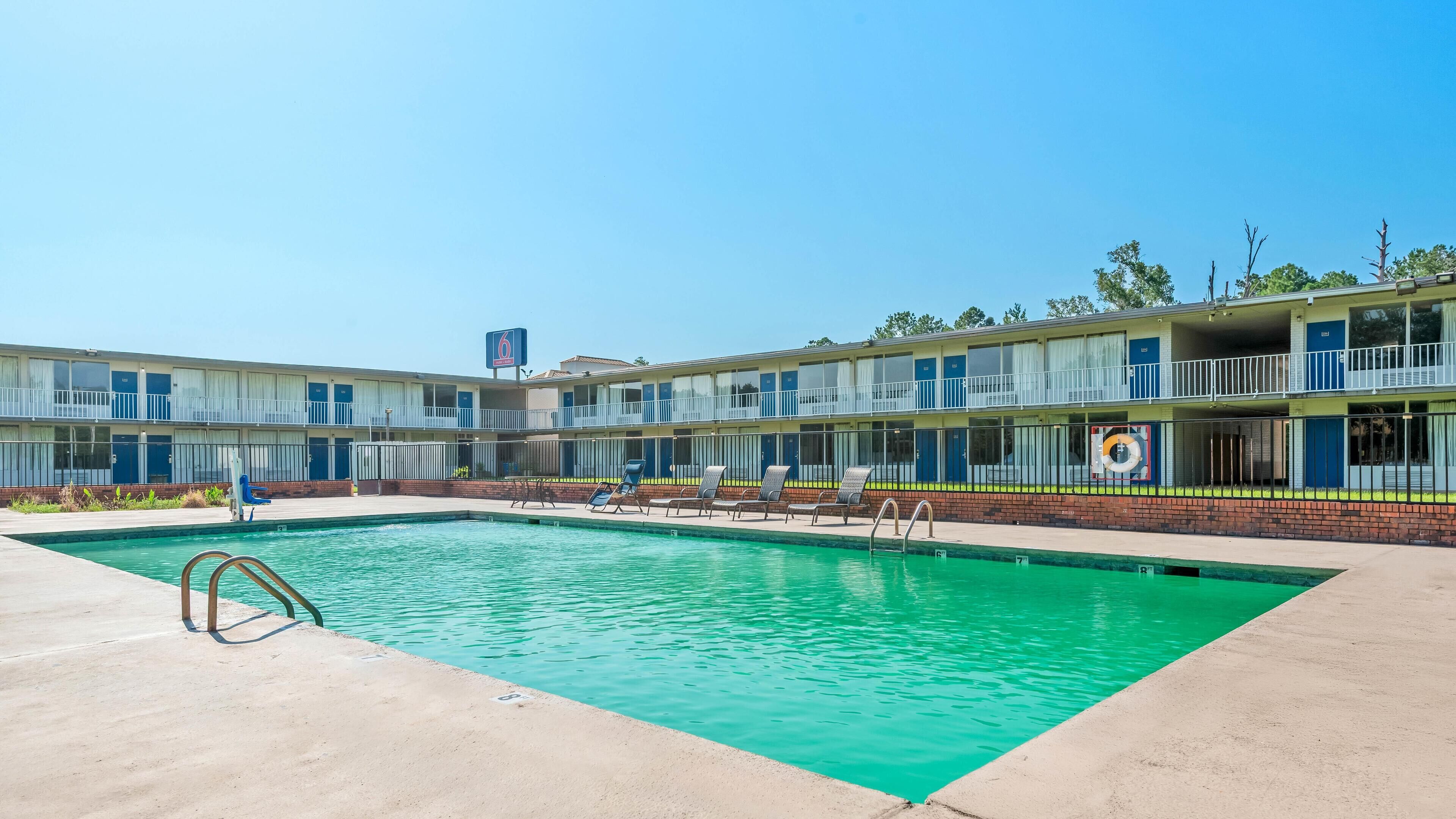 Ein Motel mit Schwimmbad, mehreren Balkonen und blauem Himmel.