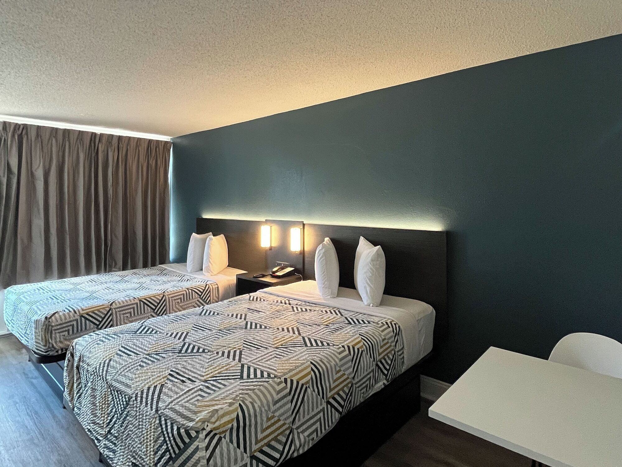 A hotel room with two beds, a desk, and a chair.
