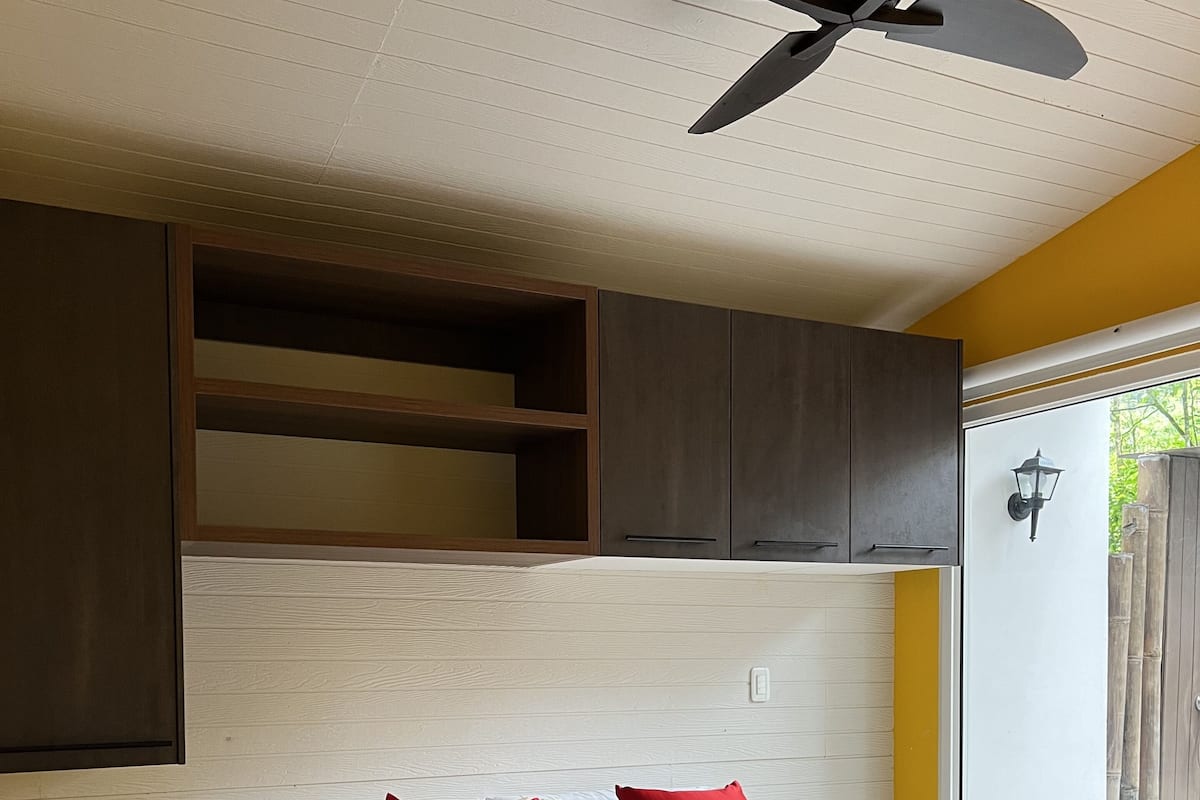 A bedroom with a bed, a ceiling fan, built-in cabinets, and a nightstand.