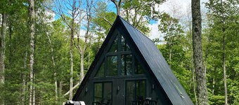 A modern A-frame, nestled in the woods with relaxing outdoor spaces and firepit.