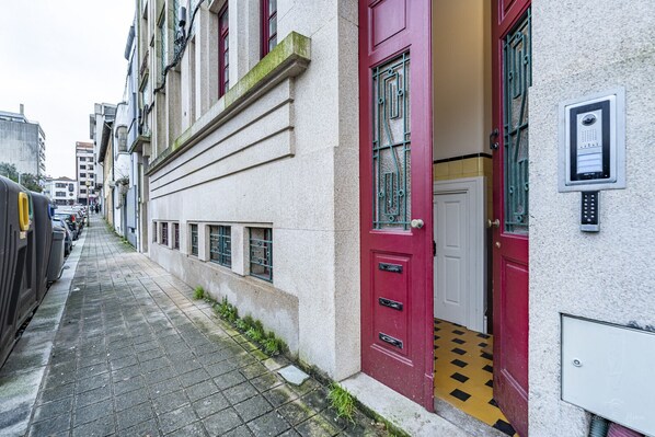 A narrow street with buildings on either side. There are cars parked along the street, and a red door is visible on the right side. - Nomads Family 3BDR City Vibe Porto (Porto)
