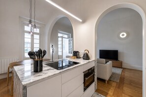 A modern kitchen with a marble countertop, integrated appliances, and a dining area with a wooden table and chairs.