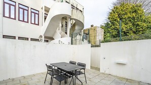 A patio with a table and chairs, a white wall, and a spiral staircase. - Nomad's Family - 3BDR Charming Hideout Porto (Porto)