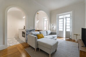 Un salon moderne avec un canapé, un téléviseur et un coin cuisine visible à travers une arche.