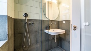 A modern bathroom with a glass-enclosed shower, a white sink, and a large mirror. - Nomad's Family - 3BDR Charming Hideout Porto (Porto)