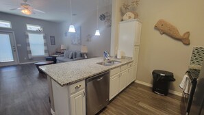 A modern kitchen with a granite countertop, stainless steel appliances, and white cabinetry.