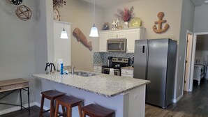 A modern kitchen with a central island, bar stools, stainless steel appliances, and decorative wall art.