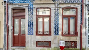 A building with a brown door, two windows with brown frames, and a red fire hydrant. - Nomad's Lux - 1BDR The Silent Nest in Bonfim (Porto)