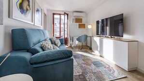 A modern living room with a blue sofa, a flat-screen TV, and a patterned rug. - Nomad's Lux - 1BDR The Silent Nest in Bonfim (Porto)