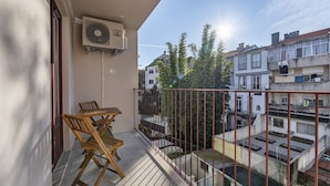 A balcony with a table and chairs, an air conditioning unit, and a view of neighboring buildings. - Nomad's Lux - 1BDR The Silent Nest in Bonfim (Porto)