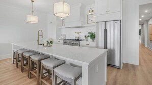 A modern kitchen with a large island, stainless steel appliances, and pendant lighting. - Luxury Condo Overlooking Downtown Fairhope #201 (Fairhope)