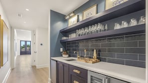 A modern kitchen with dark cabinetry, a white countertop, and a backsplash of dark tiles. - Luxury Condo Overlooking Downtown Fairhope #201 (Fairhope)