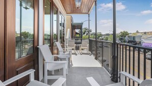 A covered outdoor area with white chairs and tables, a wooden ceiling, and a view of the street. - Luxury Condo Overlooking Downtown Fairhope #201 (Fairhope)