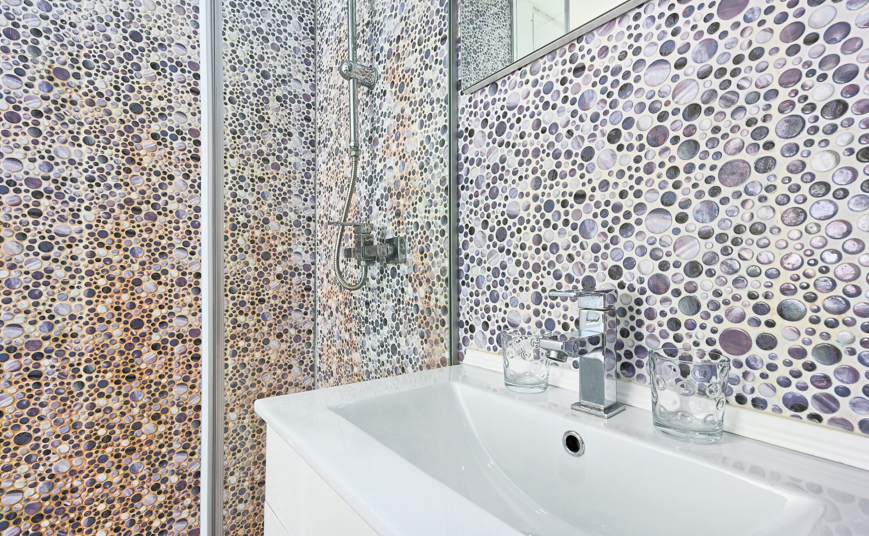 A bathroom with a sink, mirror, and shower area.