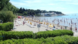 A beach with sun loungers and umbrellas, a clear sky, and a calm sea.