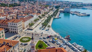 A coastal cityscape with a prominent waterfront promenade, a central roundabout, and a mix of historic and modern buildings. - Luxury Room Ana 1 in the Heart of Split (Split)