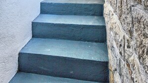 A staircase leading to a bedroom with a stone wall and a door with a light switch.