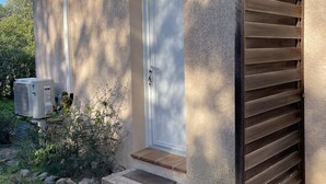 A house with a white door, a small porch, and a brown sliding door. - Studio Figari, au Calme Avec Magnifique vue sur la Montagne et les Vignes (Figari)