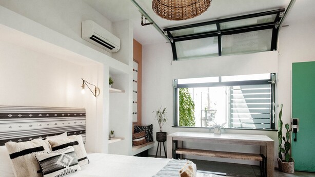 Une chambre moderne avec un grand lit, un bureau et une fenêtre donnant sur un paysage verdoyant.