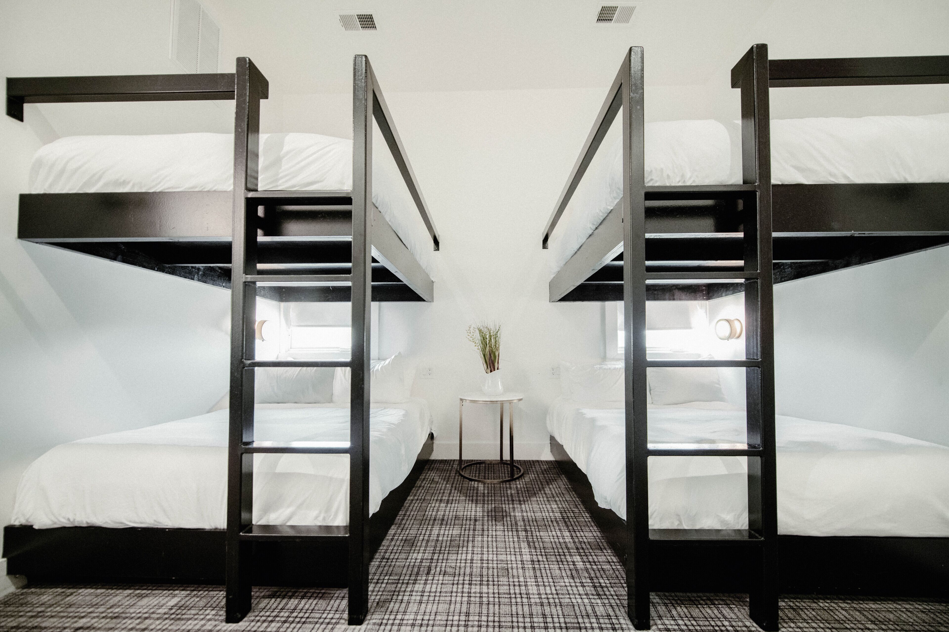 A room with two bunk beds, a small table with a vase, and a checkered floor.