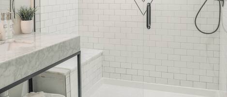 Un baño moderno con azulejos blancos tipo metro, un espejo en forma de V, una cabina de ducha de cristal y un suelo con estampado de estrellas.