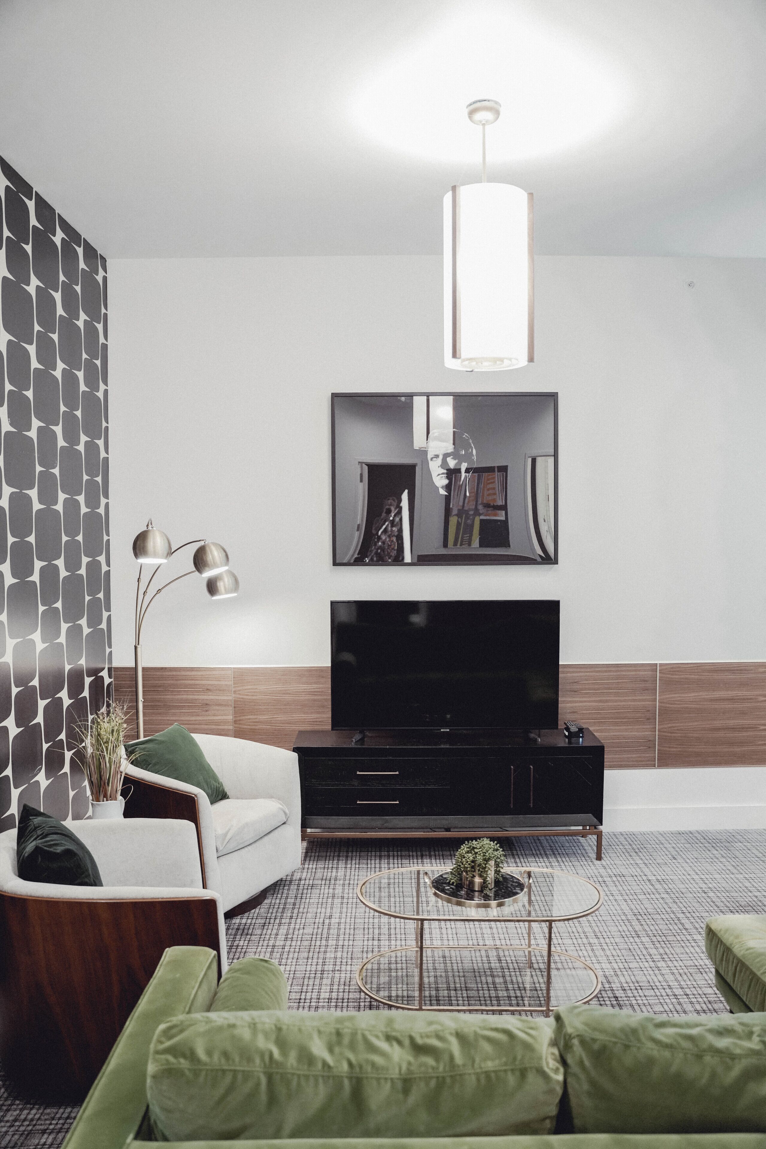 A modern living room with a flat-screen TV, a sofa, a coffee table, and a pendant light.