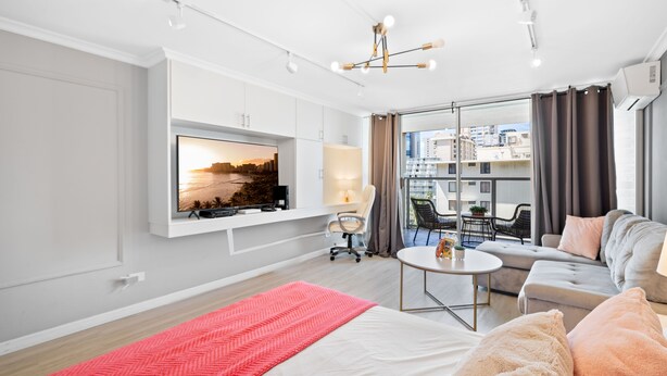 Un salon moderne avec un téléviseur à écran plat, un canapé, une table basse et un tapis rouge.