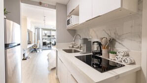 Une cuisine moderne avec des meubles blancs, une plaque de cuisson à induction noire et un évier en acier inoxydable.