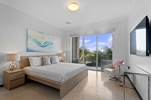 A modern bedroom with a large bed, a desk, and a TV. - Eagle Beach - Sunset Dreams 2BR condo - LV303 (Eagle Beach)