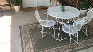 An outdoor patio with a round metal table and four chairs, a white door labeled "The Peabody Flat," and potted plants. - Aunt Minnie's Peabody Flat near Mountain View's Historic Courthouse Square (Mountain View)