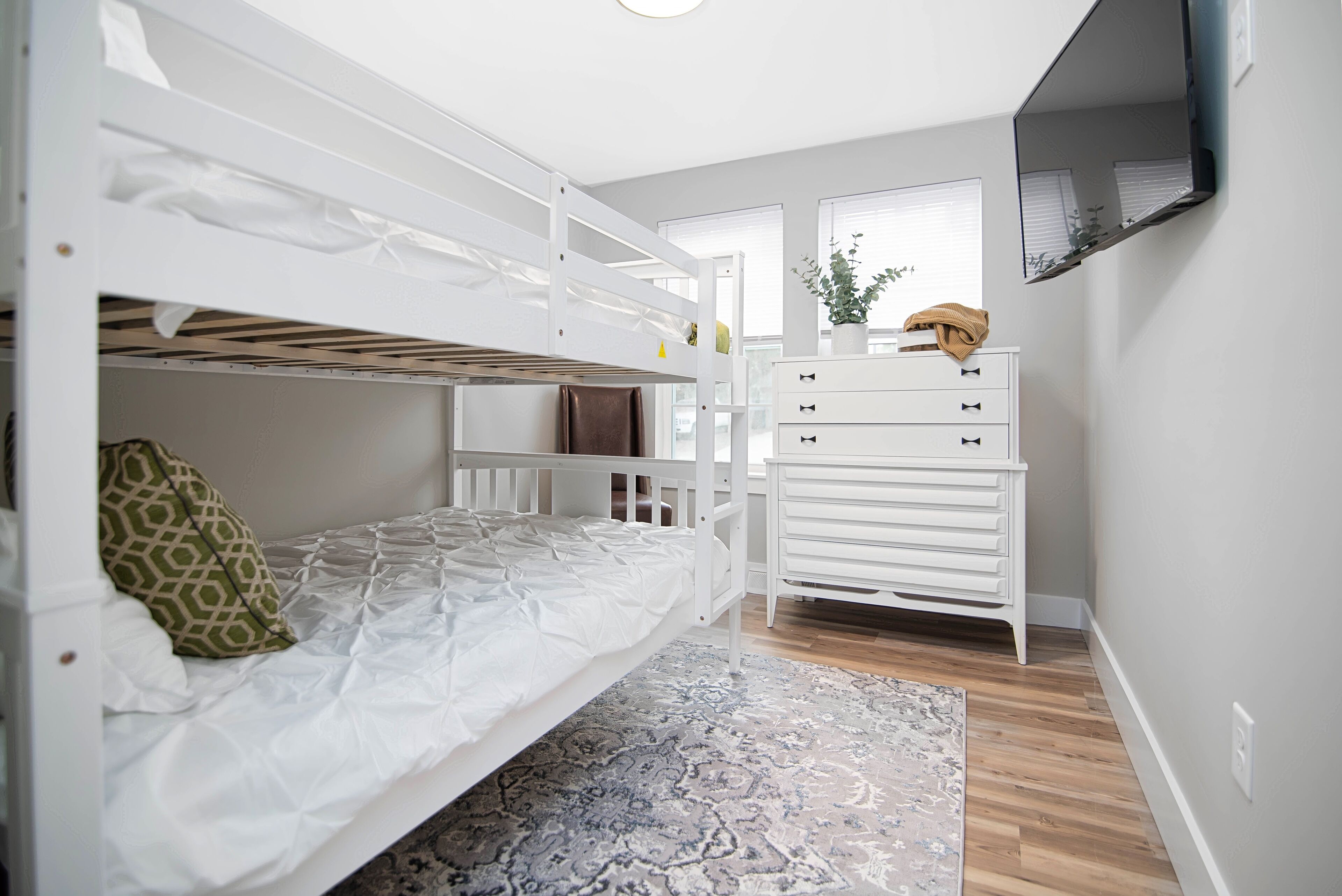 Habitación con literas, un aparador blanco y un espejo.