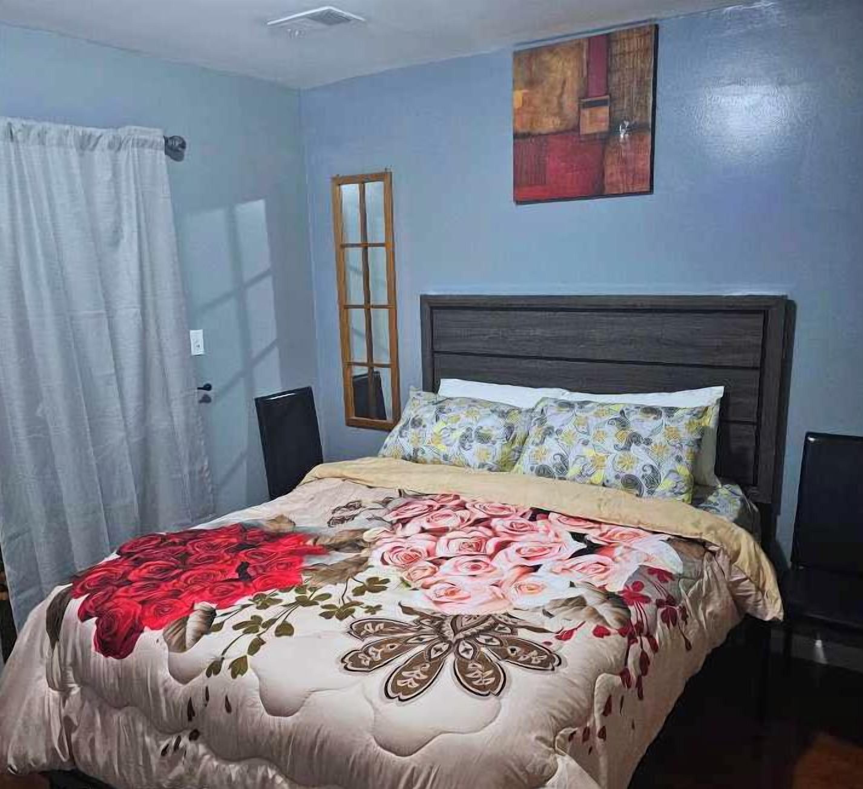 A bedroom with a bed, a window, a door, and a painting on the wall.