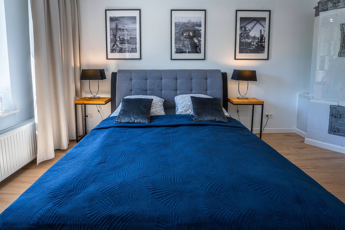 Quarto com uma cama grande, duas mesas de cabeceira com luminárias e três quadros na parede.
