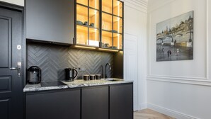 Una cocina moderna con armarios oscuros, salpicadero con estampado de espiga y unidad de almacenamiento empotrada con puertas de vidrio.