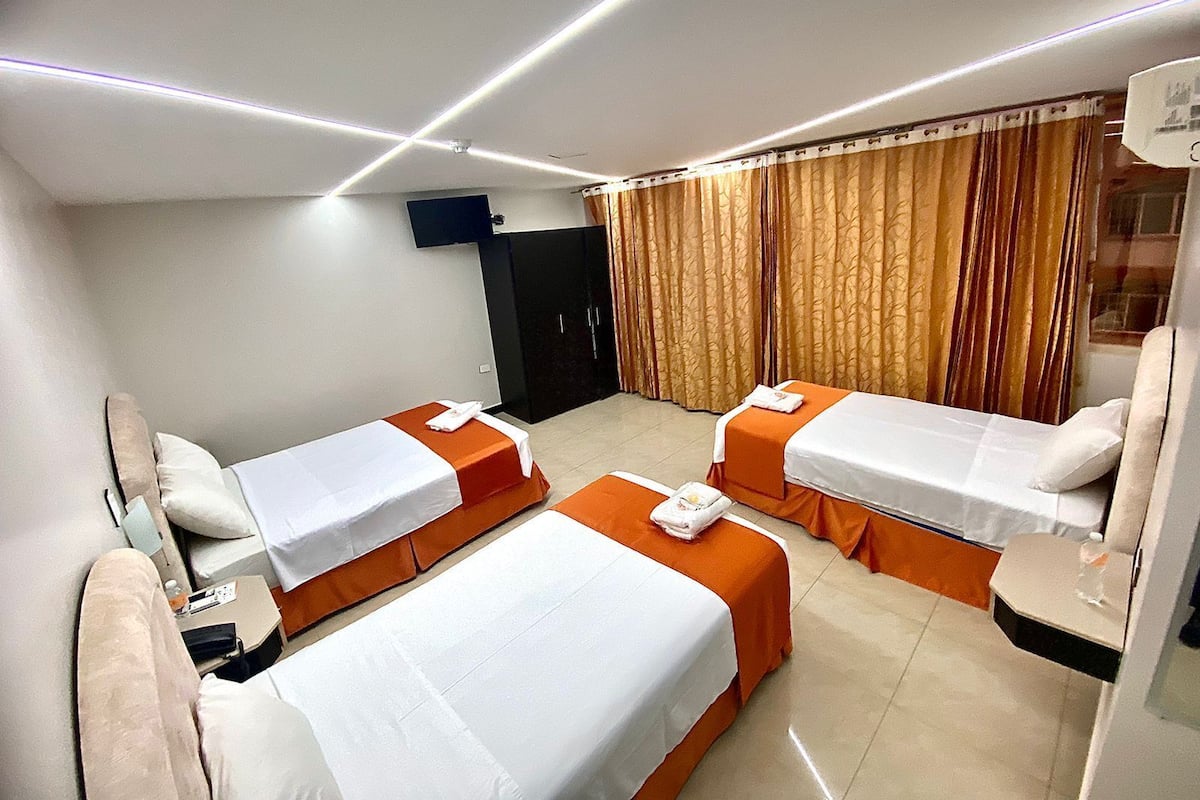 A hotel room with two single beds, a desk, a chair, a TV, and a wardrobe.