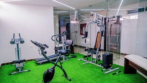 A gym with various exercise equipment, including a treadmill, elliptical, and weight machines, on a green floor. - BRITNEY HOTEL MACHALA (Machala)